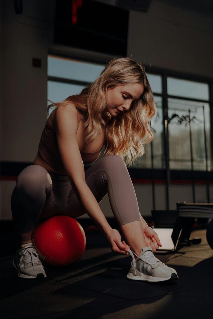 A girl tying shoelaces while working out 